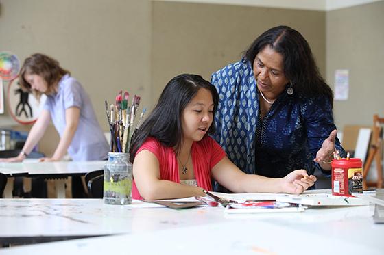 Photo of a Chatham University faculty member assisting a student in an art studio